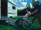 Gentleman pushing his wife in wheelchair into motorhome