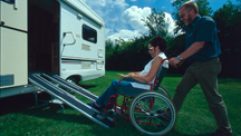 Gentleman pushing his wife in wheelchair into motorhome