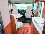 The white upholstery and trim sitting alongside the mid-toned wood gives the Hymer Exsis-i 578's interior an elegant and refined feel