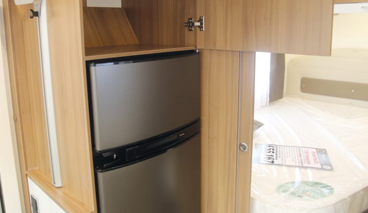 A large fridge/freezer sits midships on the offside of the motorhome, opposite the kitchen, with a handy cupboard above it