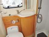 The corner washroom has a separate shower cubicle, swivel toilet and fixed basin with storage below