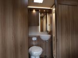 The toilet and vanity area in the washroom features a lot of wood, plus tasteful ambient lighting