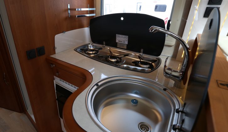 The L-shaped kitchen has three gas burners, a smart mixer tap and a round stainless steel sink