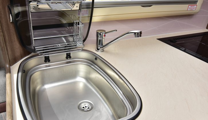 The glass cover to the large stainless-steel sink carries a chrome drainer – closing the cover creates more food-preparation space