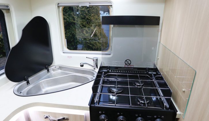A three-burner hob sits atop the combination oven and grill while to the left, the sink has a hinged flap in preference to a removable drop-in cover