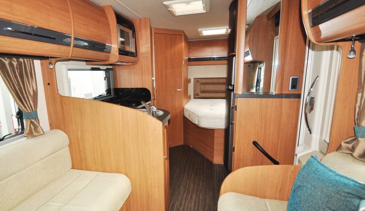 Overhead lockers line both sides of the Auto-Trail Tracker FB, but they all lack positive catches; amidships is the L-shaped kitchen and cooking appliances, with a tall fridge/freezer across the aisle