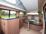 The L-shaped kitchen hides the compressor fridge and combination oven/grill behind a solid door with built-in shelves