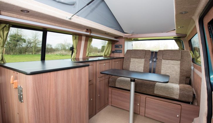 The L-shaped kitchen hides the compressor fridge and combination oven/grill behind a solid door with built-in shelves