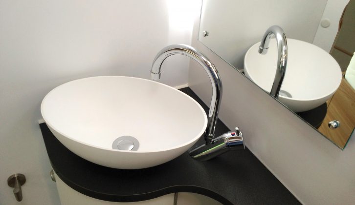 This stylish circular sink has a smart mixed tap, while there's a large mirror behind