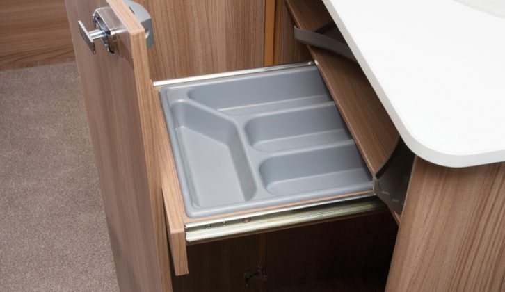 The L-shaped kitchen unit helps makes the most of the available space, while under-sink storage is accessed via this space-saving folding door