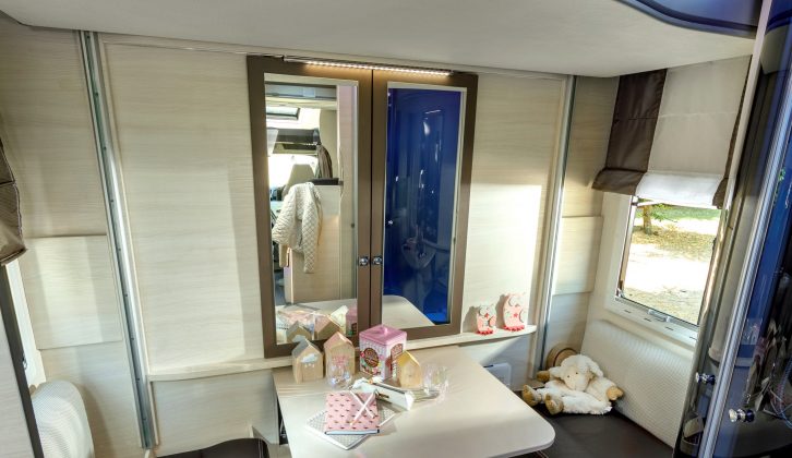 The rear lounge feels large thanks to the wardrobe's mirrored doors, and has a pair of facing seats, with a fold-up table in the middle – note the retracted bunks above