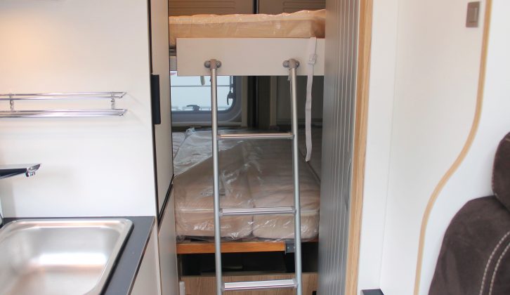 The spacious upper bunk is accessed via a ladder, which sits beside the washroom’s tambour door