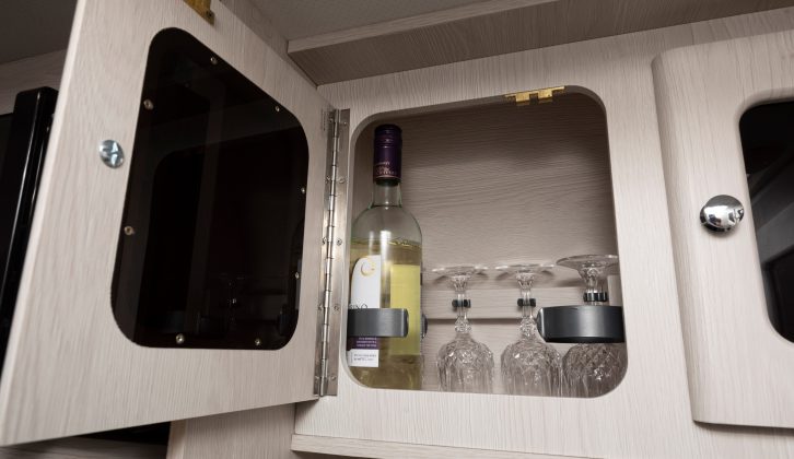 One of the kitchen cupboards contains storage for two wine bottles and a set of crystal glasses, and there's storage for four more wine bottles beneath the travel seat