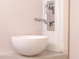 The shower extends out from the large salad bowl-style handbasin in the corner of the washroom, and you also get a towel hook