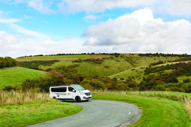 A motorhome driving round a bend on a bright day