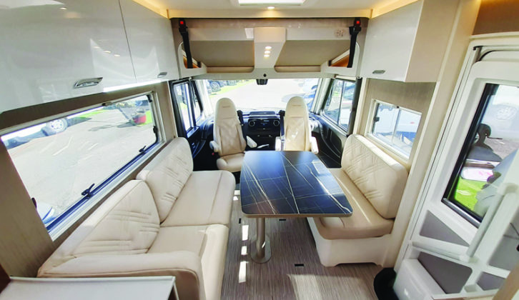 Large pedestal table folds in half for easy access from the cab, and there are two travel seats enclosed under the parallel settees