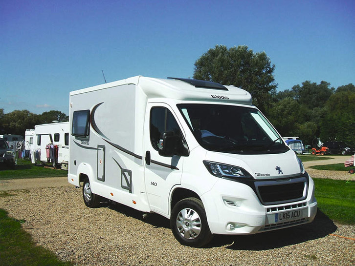 A motorhome parked on gravel, with a blue sky in the background