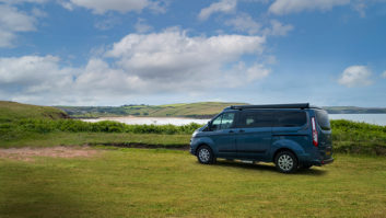 Exterior shot of the campervan, parked on grass by water