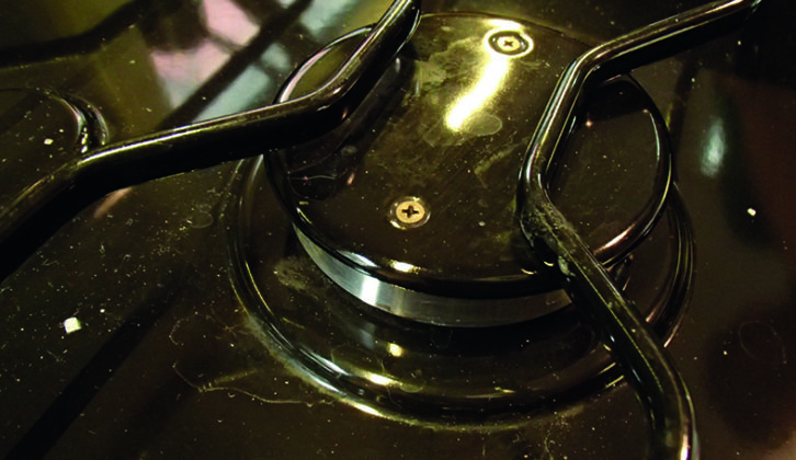Gas burner under the trivet, showing two screws allowing access for cleaning and checking