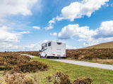 A motorhome driving up a slight incline on a bright day