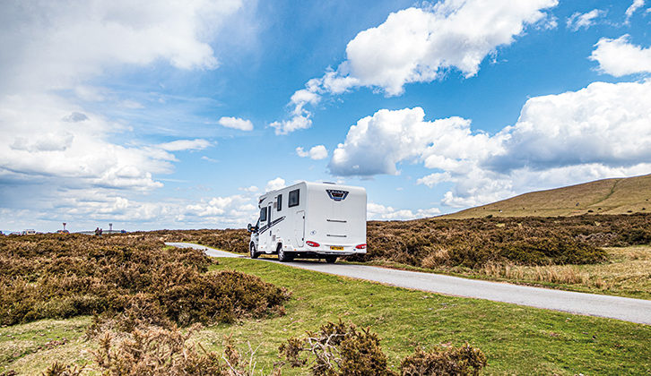 A motorhome driving up a slight incline on a bright day