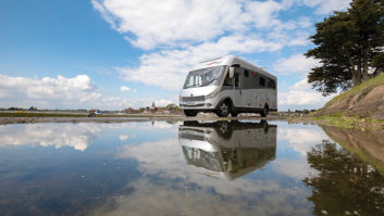 A motorhome reflected in a pool of water on a bright day
