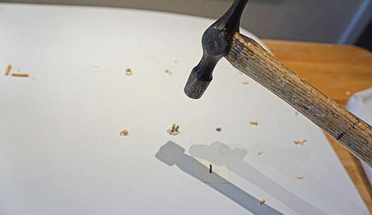 A hammer being used to knock the matchsticks into place