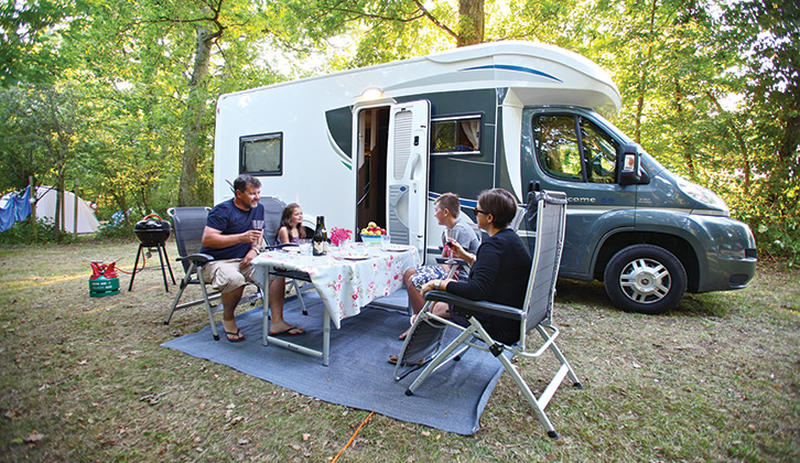 A family eating lunch at a table outside a motorhome