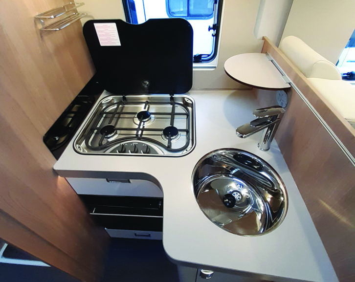 Compact kitchen, but the sink cover can be clipped to the wall for more serving space