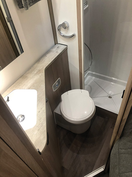The washroom provides a spacious square shower cubicle with three shelves, swivelling Thetford toilet and a reasonably sizeable handbasin