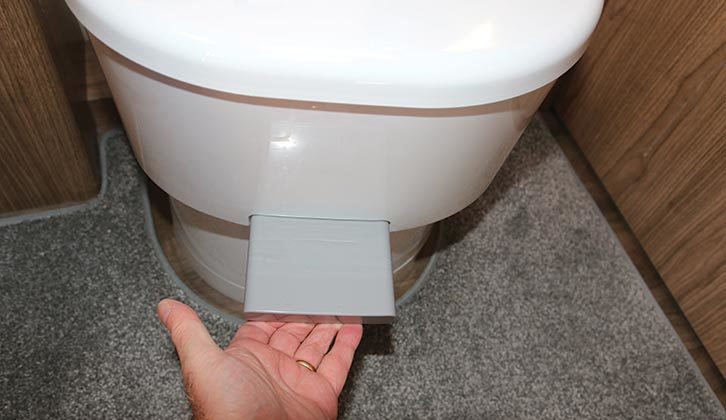 The lever being pulled to open the toilet blade