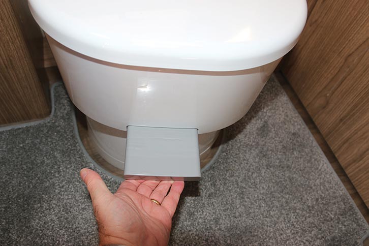 The lever being pulled to open the toilet blade
