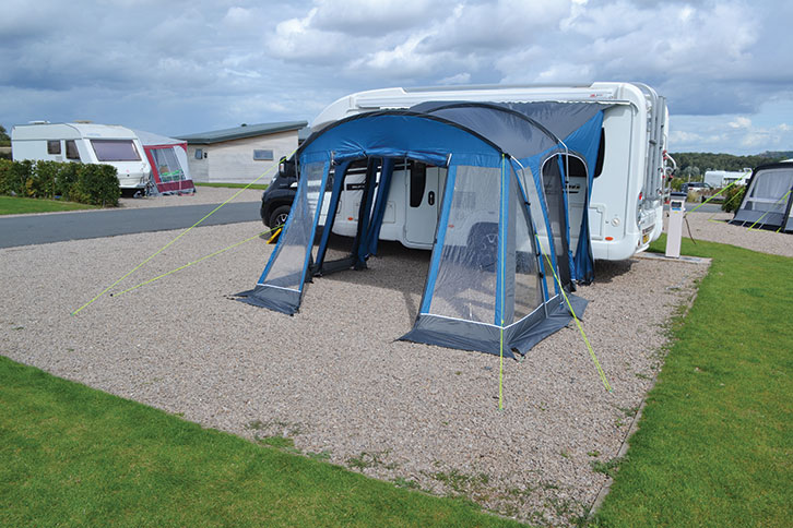 An awning set up on a gravel pitch 
