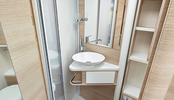 The washroom has a smart handbasin and shelving