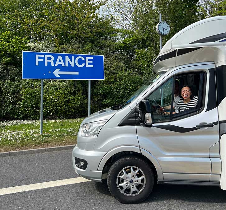 Motorhome turning left as sign points to France