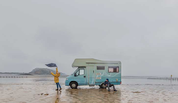 Person on beach on overcast day by motorhome