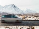 A campervan driving past Glencoe in winter