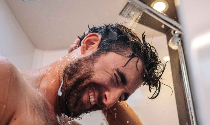 A closeup of a man's face while he showers