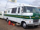 A motorhome and trailer with a green stripe along the paintwork