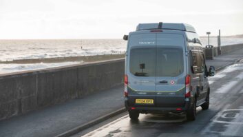 A campervan being driven along the seafront