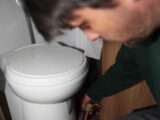 A technician using a damp meter around hte toilet