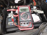 A multimeter displaying a reading of 12.80V