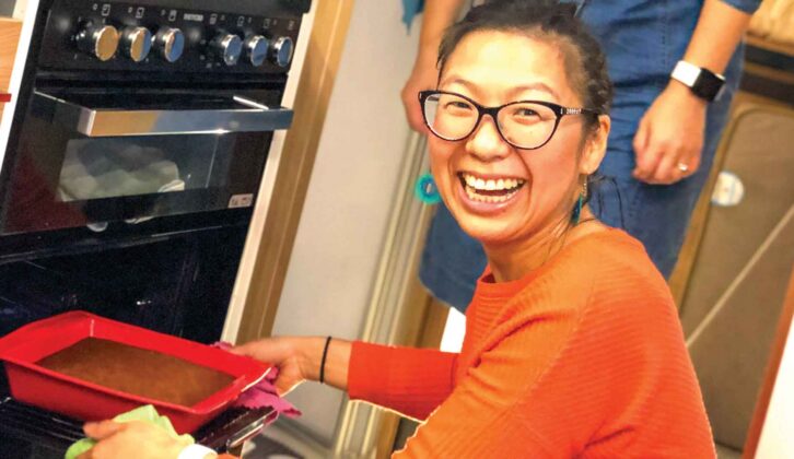 A woman smiling at the camera as she puts a tray in the cooker