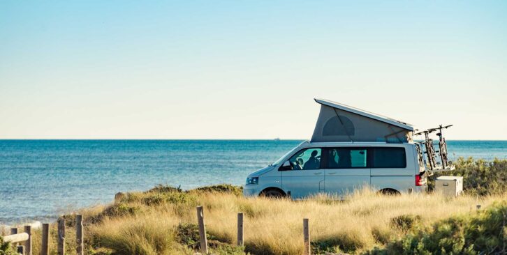 A campervan with its roof up and a bike rack on the back