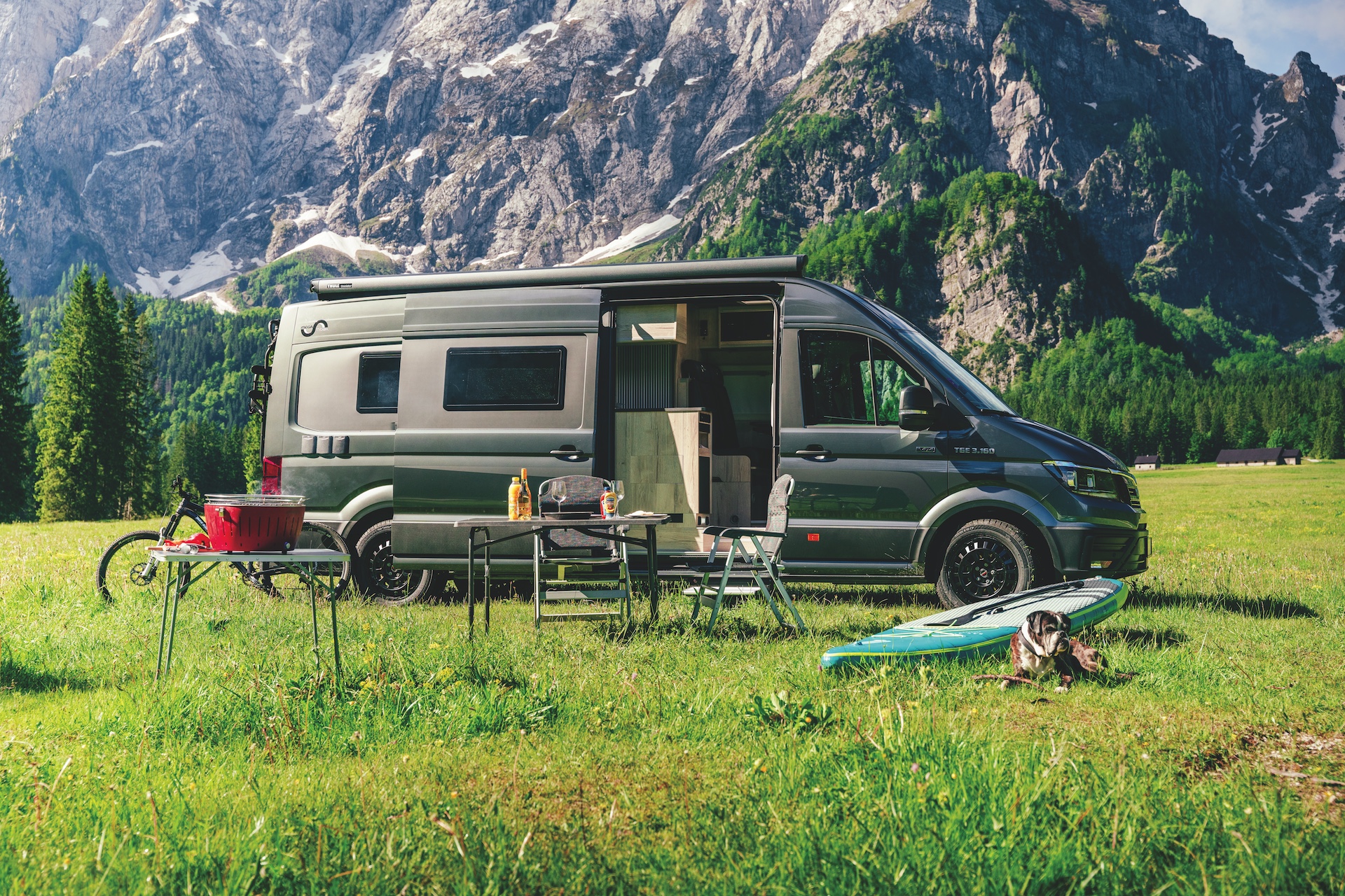 MegaMobil campervan parked in a field and surrounded by outdoor-activity products