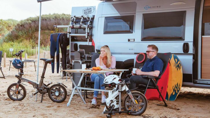 A man and woman sitting under a canopy with folded bikes nearby