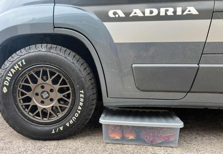 A lidded plastic box with shoes in by a motorhome