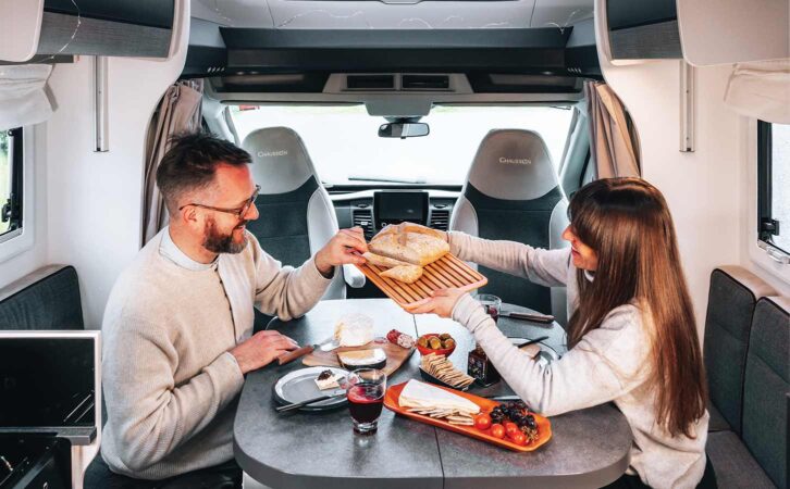 Two people eating inside their leisure vehicle