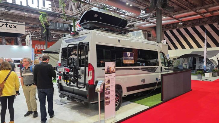 A campervan with a roof box and a bike rack at the rear
