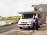 An overcab motorhome being filled up at a garage